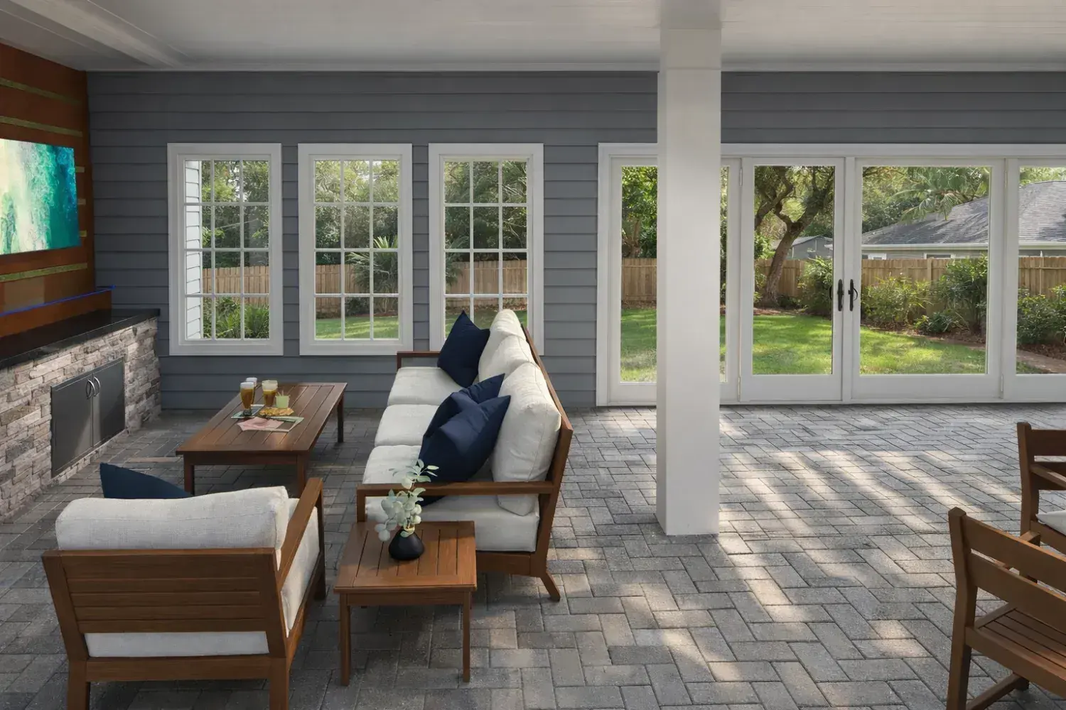 3D rendering: covered lanai with deep sofas, a wall-mounted TV and French doors to the house